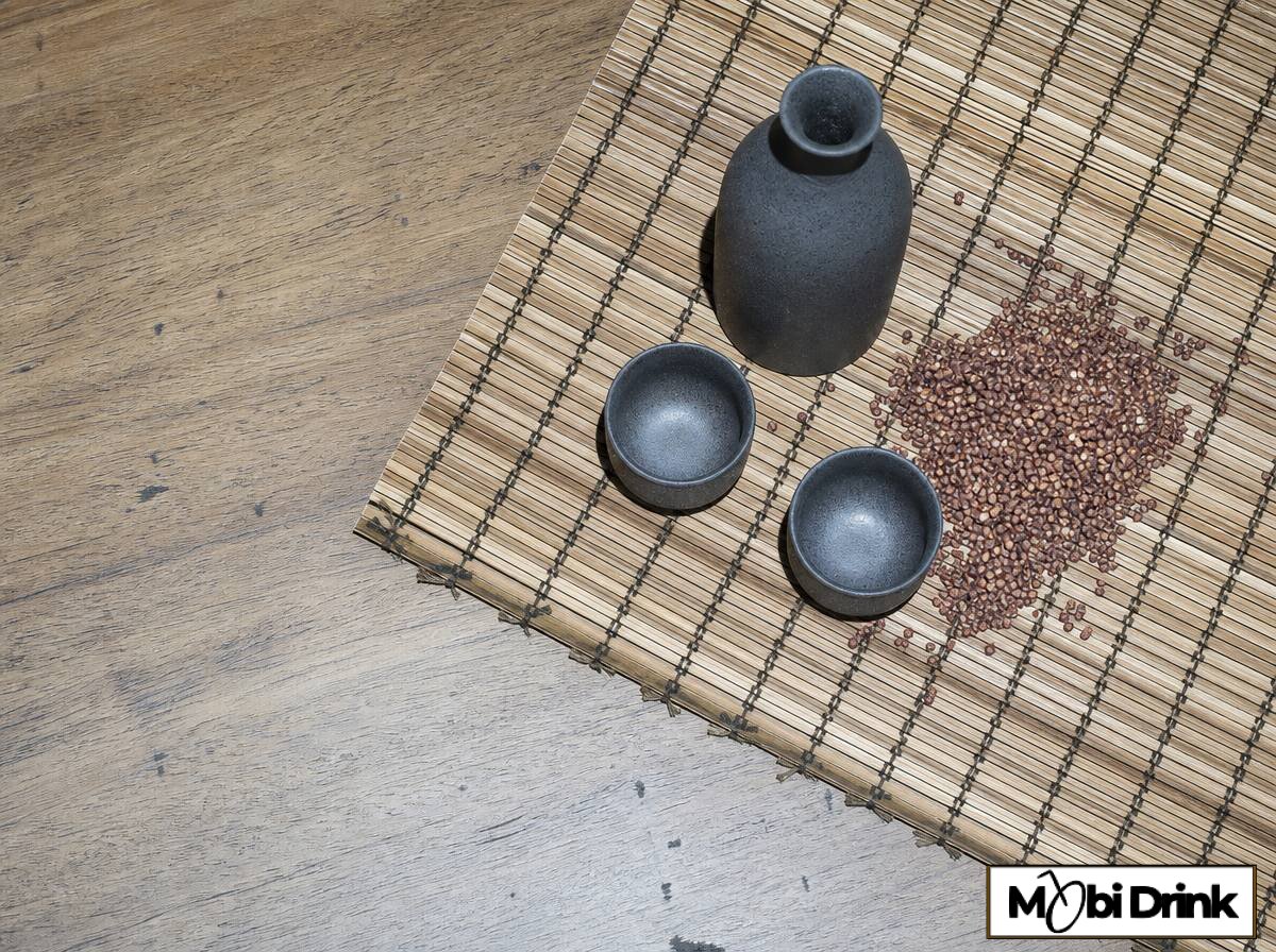 Ceramiczna butelka baijiu z tradycyjnymi kieliszkami i ziarnami sorgo na stole