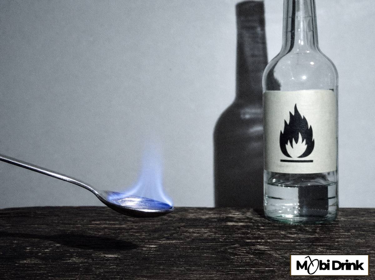 Płonący niebieski płomyk nad łyżką z bardzo mocnym przezroczystym alkoholem